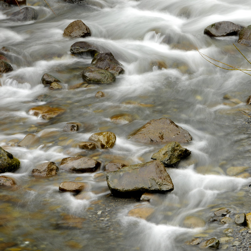 Long exposure of silky white water flowing through rounded river stones