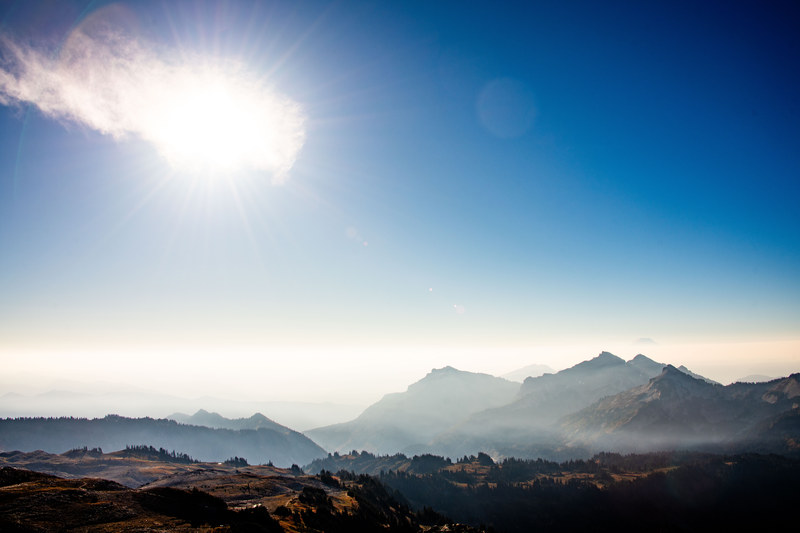 Smoky haze over layered Cascade mountain ridgelines with sun and atmospheric depth