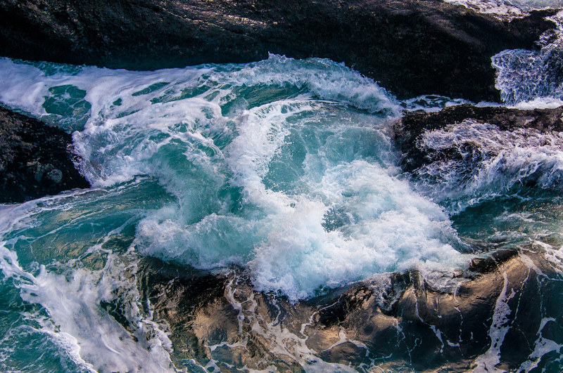 Turquoise ocean water swirling violently through coastal rock formations at Cape Flattery